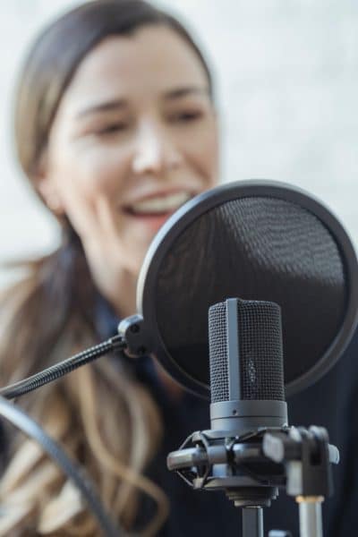 Lady warming up voice behind mic